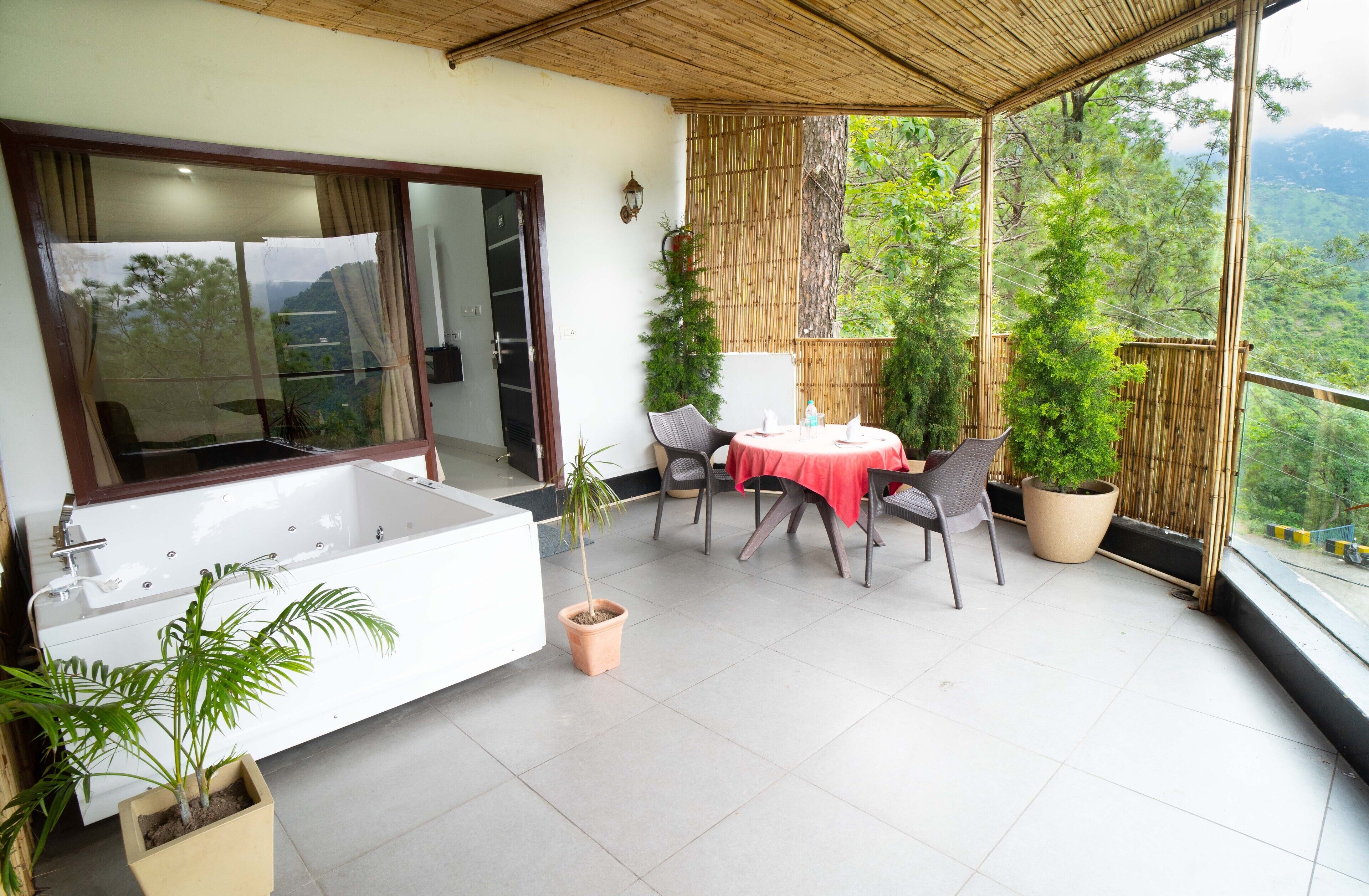 Een balkon met een witte badkuip, een tafel met stoelen en potplanten.