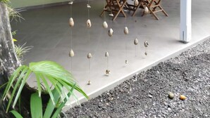 Un área de comedor al aire libre con techo cubierto, decoraciones de cerámica colgantes y una mesa preparada para dos.