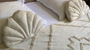 Una cama con una colcha beige texturizada, dos almohadas y un cabecero decorativo.