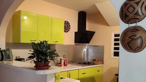 Una cocina con una isla central, gabinetes verdes, una campana extractora negra y decoración en la pared.