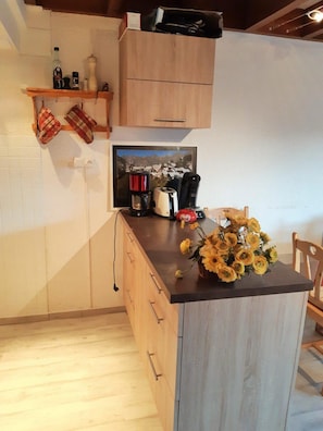 Eine Küche mit Holdekor, einer Arbeitsplatte mit Kaffeemaschine, Toaster und einer Vase mit gelben Blumen.
