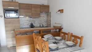 A compact kitchen with wooden cabinets, a built-in microwave, and a stone backsplash.