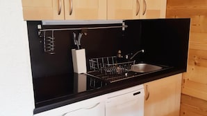 A compact kitchen with a black countertop, white cabinetry, and a dishwasher.