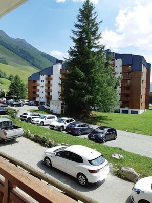 A multi-story hotel with a parking lot, surrounded by greenery and mountains. - 50m from ski slopes, 1st floor, view ski slopes, balcony, tv, 30m², Les 2 Alpes (Les Deux Alpes)