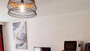 A compact kitchen with a microwave, toaster oven, and a flat-screen TV on a wooden cabinet.