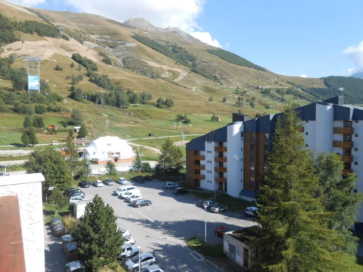 A hotel with multiple floors, a parking lot, and a mountainous backdrop.