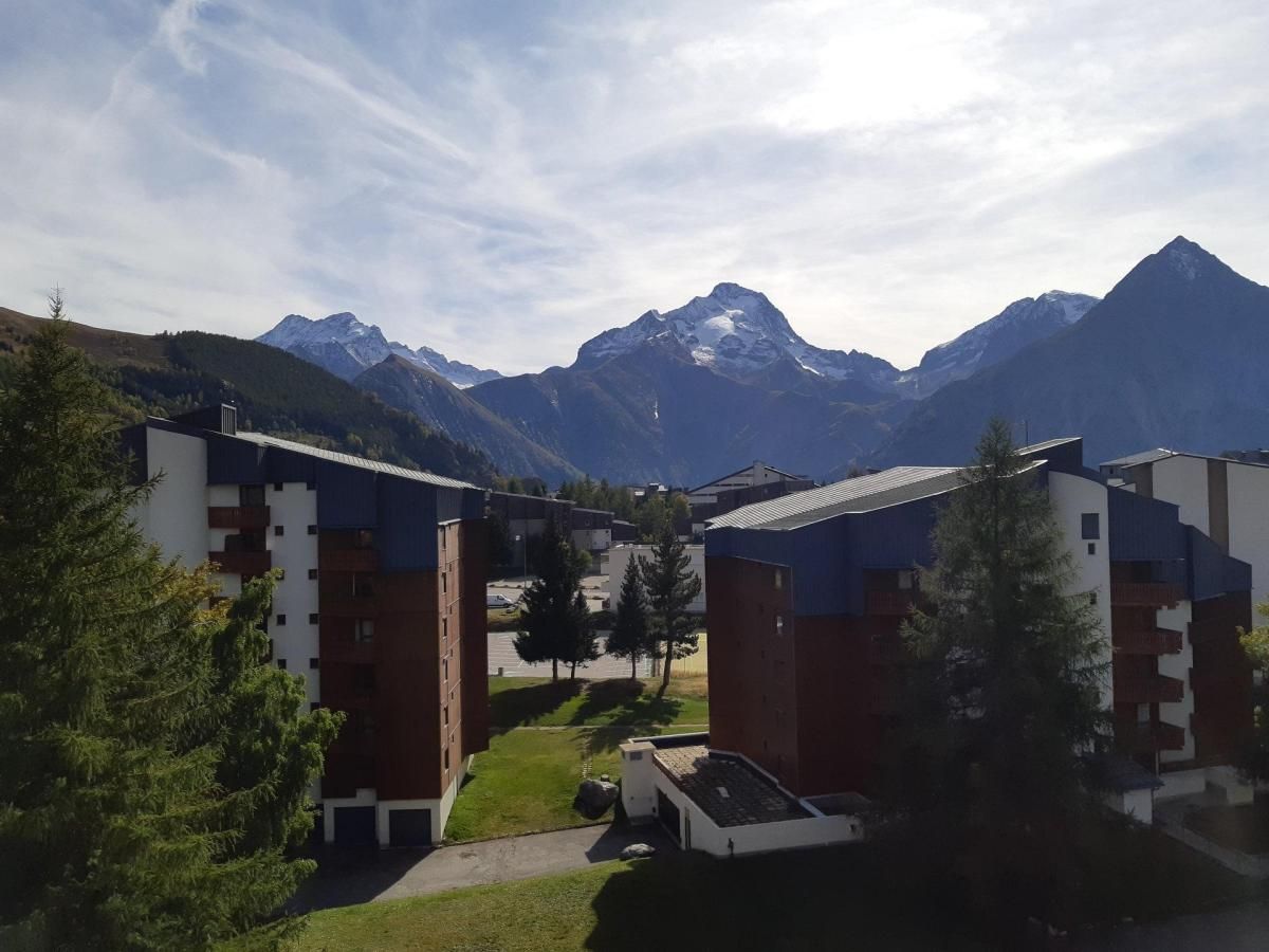 A residential area with modern buildings, a clear sky, and mountains in the background.