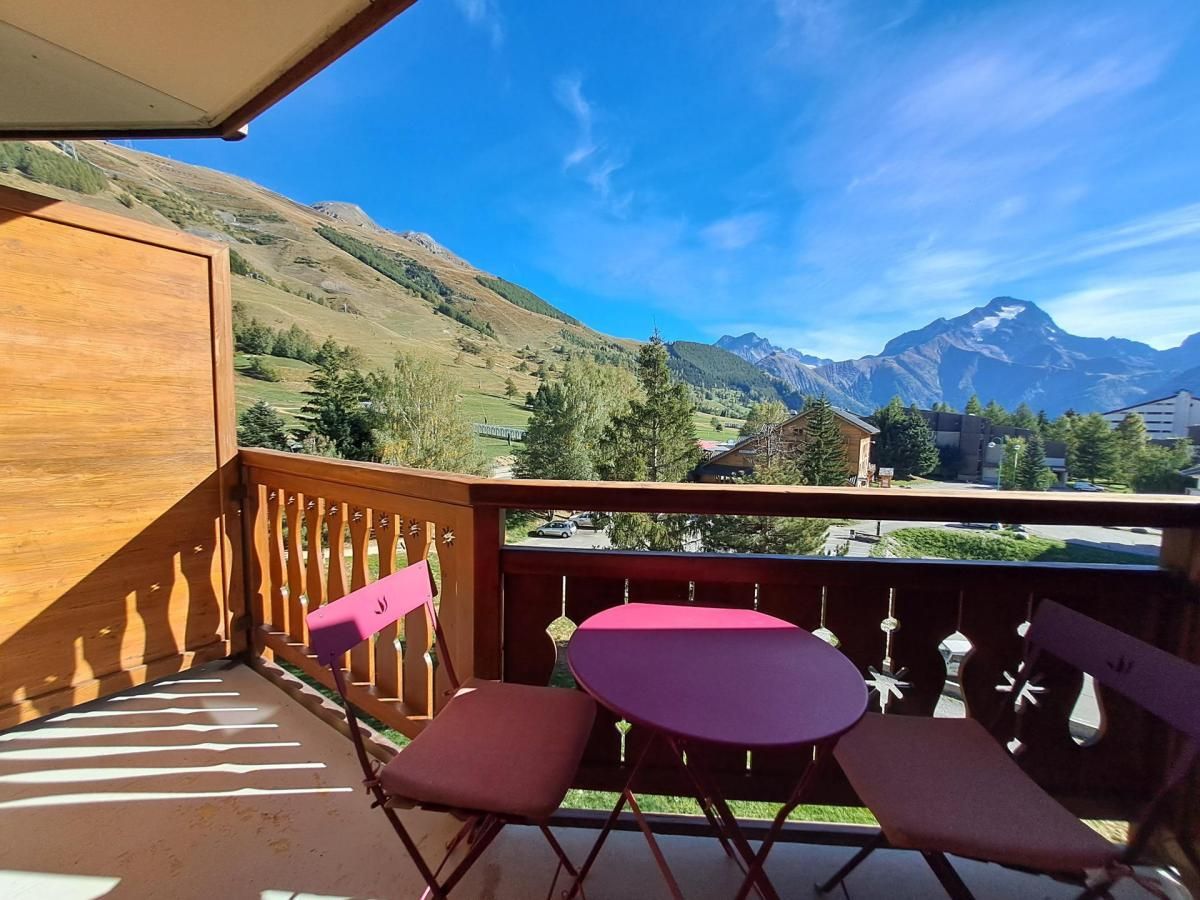 Ein Balkon mit Blick auf Berge, einem Holgitter und einem Tisch mit Stühlen.