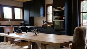 Una cocina moderna con armarios oscuros, una mesa de comedor de madera y un plaid de piel.