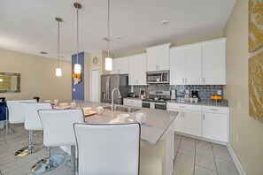 A modern kitchen with white cabinets, stainless steel appliances, and a central island with seating.