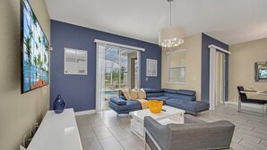 Ein modernes Wohnzimmer mit einem blauen Sofa, einem weißen Couchtisch und einem Essbereich mit Tisch und Stühlen.