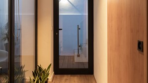 Un pasillo con suelo de madera, una puerta corredera de vidrio y una puerta de madera que da a un balcón.