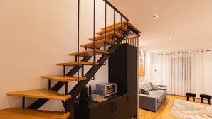 Una sala de estar moderna con una escalera de madera, un sofá gris y una alfombra estampada.