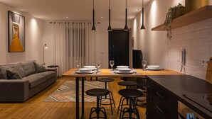 Una cocina moderna con una mesa de comedor preparada para cuatro personas, un sofá y una barra.
