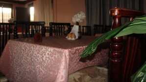 A dining area with a table covered in a patterned tablecloth, chairs around it, and a number sign '9' on the table. - Atotti Prime City Hotel (Soroti)