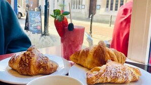 A table with croissants and a coffee cup, with a view of a building through a window. - The Best Apartment in Canterbury (Canterbury)
