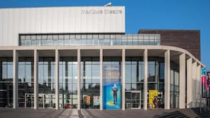 A modern building with a sign reading "marlowe theatre" and a poster advertising "Curious Incident". - The Best Apartment in Canterbury (Canterbury)