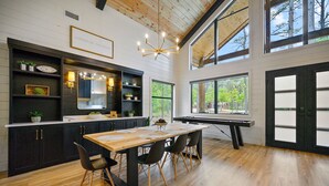Een moderne keuken met een houten eettafel, zwarte stoelen en een groot raam.