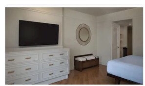 Relax in a serene space with a large flat-screen TV, dresser, and comfortable bed.