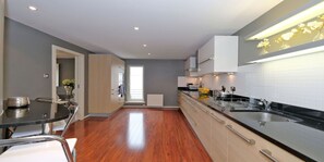 Enjoy cooking in this well-equipped kitchen with a stainless steel sink, wooden dining table, and modern countertop.