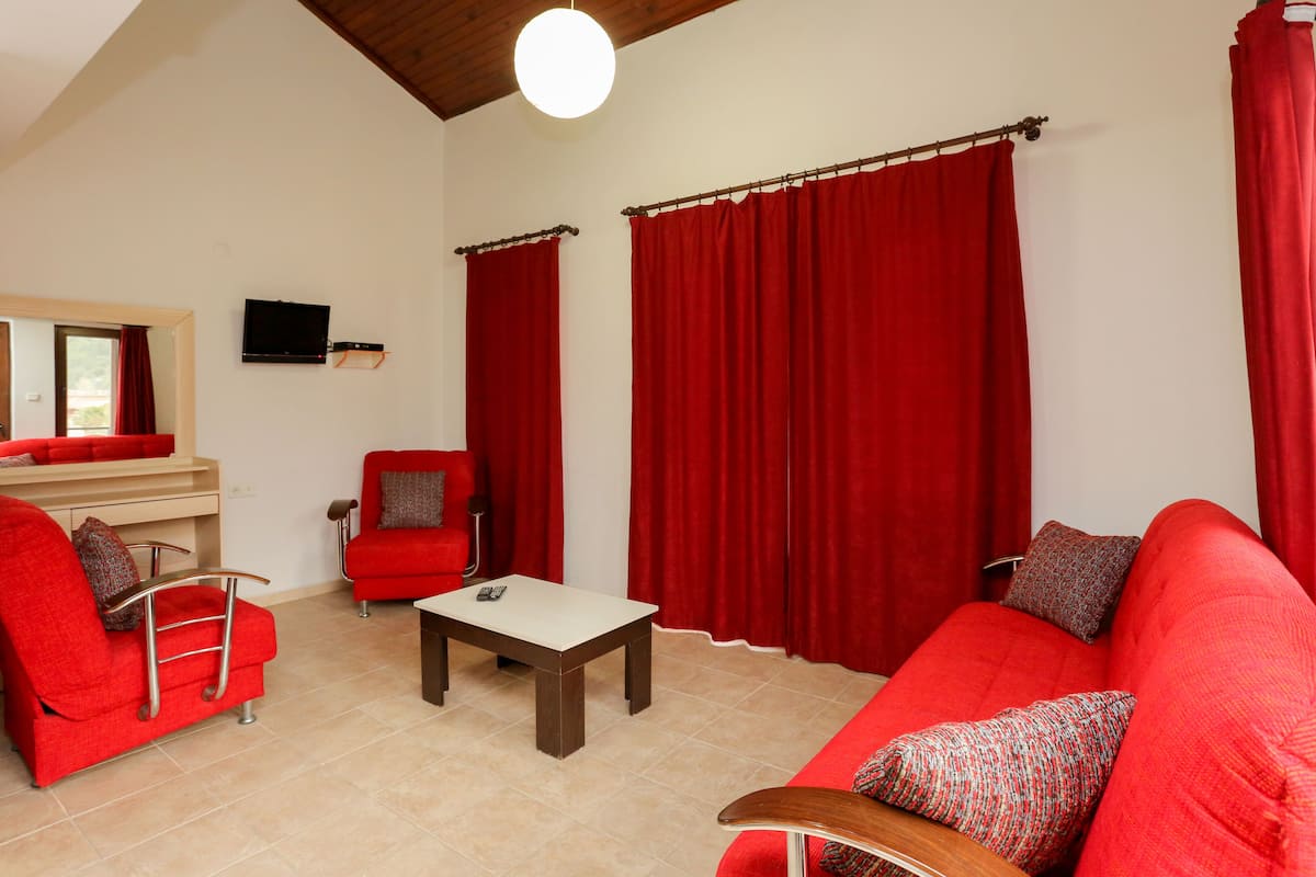 Una sala de estar con muebles rojos, un televisor de pantalla plana y una mesita.