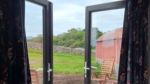 Une pièce dotée d’une grande porte-fenêtre coulissante qui donne sur un espace extérieur avec une terrasse en bois et des chaises.