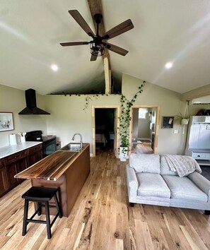 A spacious kitchen with a wooden countertop, a ceiling fan, and a dining area with a sofa. - StarGazer 2.0 FARM cottage, just 20 mins to hocking hills. w/fast internet (McArthur)