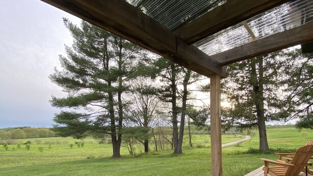 A wooden deck with a table and chairs, overlooking a grassy field and trees. - Toasted Marshmallow (w/fast internet) & baby goats! Farm 20 min to Hocking Hills (McArthur)