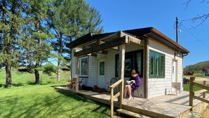 A small wooden cabin with a porch, surrounded by a grassy area and trees. - Toasted Marshmallow (w/fast internet) & baby goats! Farm 20 min to Hocking Hills (McArthur)