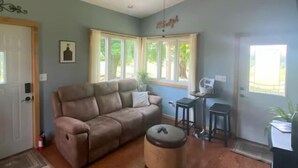 A spacious living room with a beige sofa, a ceiling fan, and a small table with a chair. - Toasted Marshmallow (w/fast internet) & baby goats! Farm 20 min to Hocking Hills (McArthur)