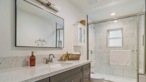 Un bagno moderno con uno specchio grande, un lavandino, un water e una cabina doccia in vetro.