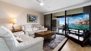 A modern living room with a white sofa, a wooden coffee table, and a large flat-screen TV.