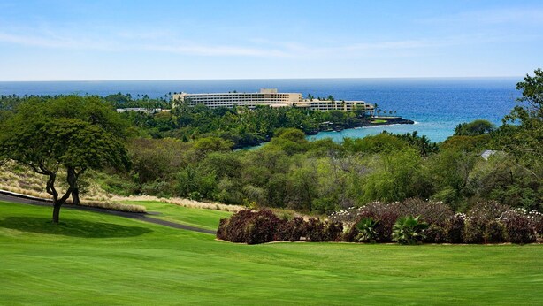 A golf course with a view of a hotel and ocean.