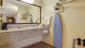 A bathroom with a granite countertop, a sink, a mirror, a towel rack, and a hand dryer.
