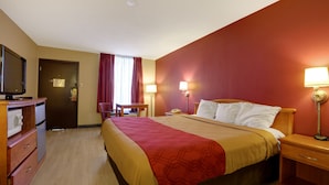 A hotel room with a bed, bedside tables, a desk, a chair, a TV, and a wardrobe.