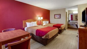 A hotel room with two beds, a wooden desk, a chair, a television, and a bathroom with a mirror and sink.