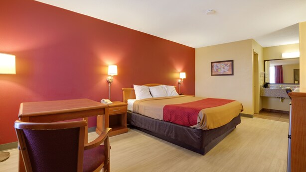 A hotel room with a bed, bedside tables, a desk, and a chair.