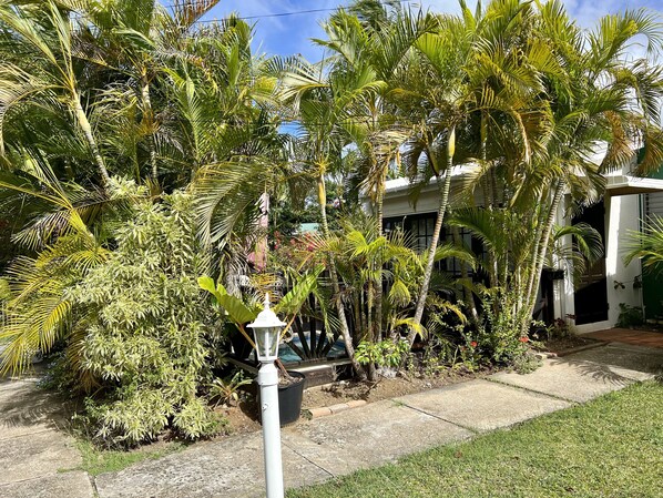 A lush garden with various tropical plants and a white lamp post.