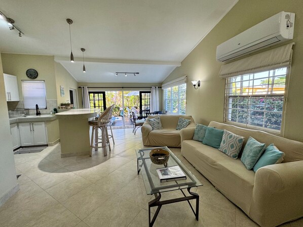 A spacious living area with a sofa, coffee table, and a dining area with chairs and a table.