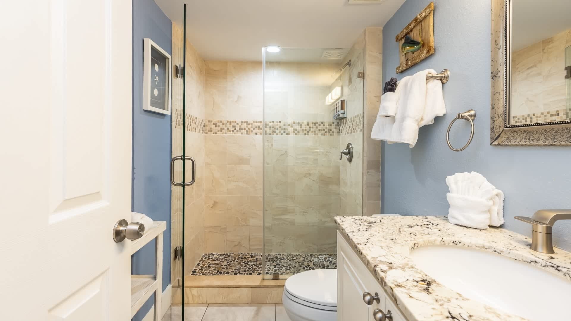 Une salle de bain moderne avec une douche à parois de verre, un lavabo en marbre et un grand miroir.