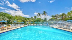 A swimming pool with lounge chairs and umbrellas, surrounded by palm trees. - Starfish Seas Ocean Pointe 1302 King/Queen 2BA 2BR (Tavernier)