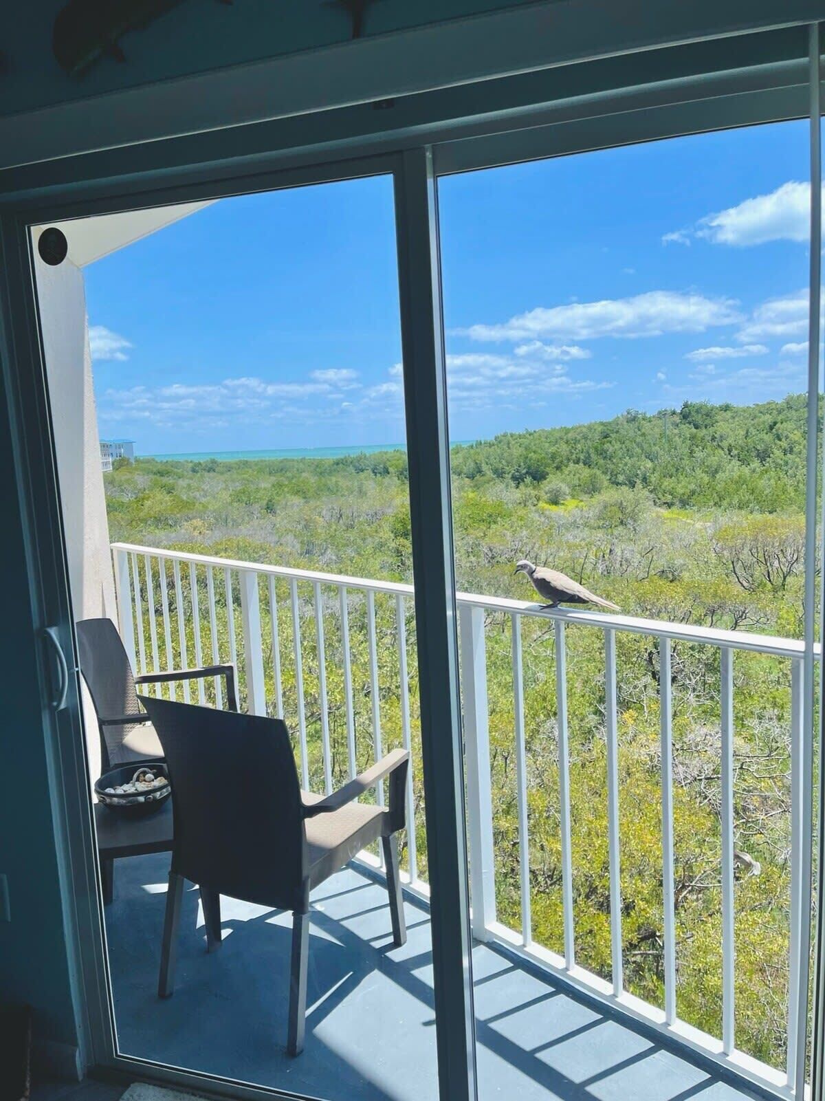 A balcony with a view of a forested landscape and a clear sky.