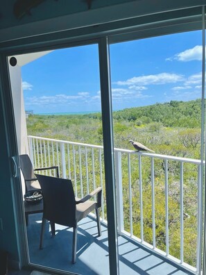A balcony with a view of a forested landscape and a clear sky.