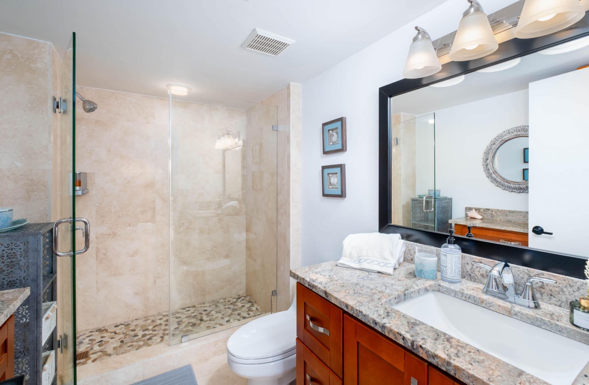 Une salle de bain moderne avec une douche à parois de verre, un grand miroir et un comptoir en granit.