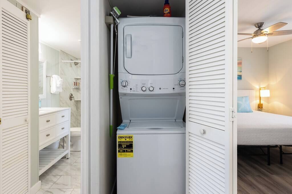 Een praktische wasruimte met een wasmachine, een droger en een klein schap met schoonmaakspullen.