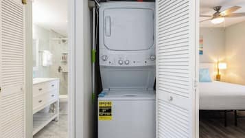 Een praktische wasruimte met een wasmachine, een droger en een klein schap met schoonmaakspullen.