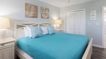 Ein Schlafzimmer mit Bett, Nachttischen, Deckenventilator, Kunstwerken und einem Kleiderschrank.