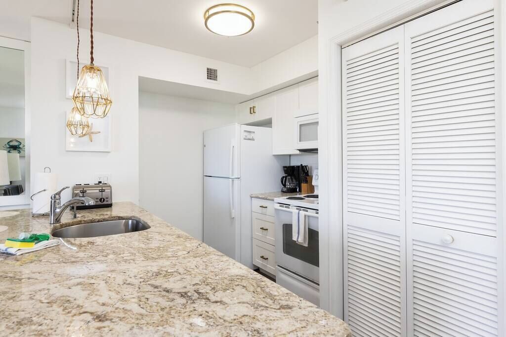 A modern kitchen with white cabinets, a granite countertop, a built-in oven, and a microwave.