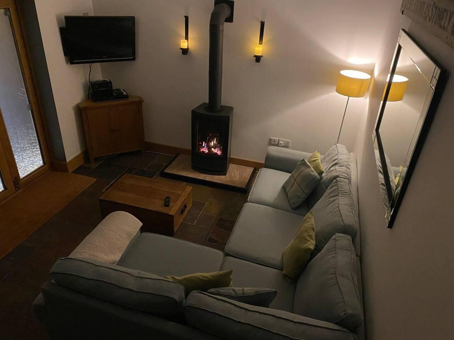 Ein Wohnzimmer mit Sofa, Fernseher, Kamin und Lampe.