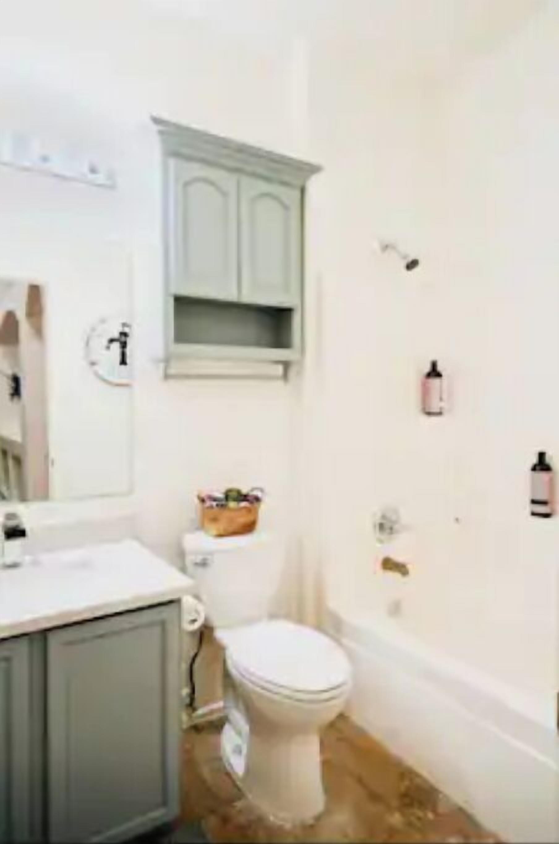 A bathroom with a toilet, sink, cabinet, and bathtub.